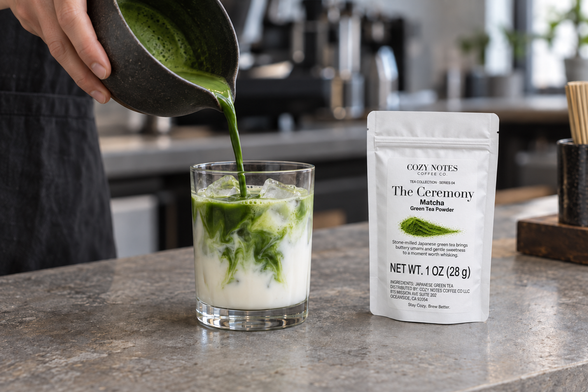 Matcha poured into an iced latte beside The Ceremony matcha pouch on a café counter.