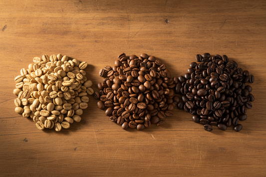 Three coffee roast levels compared side by side — light, medium, and dark roasted beans on a warm wooden surface