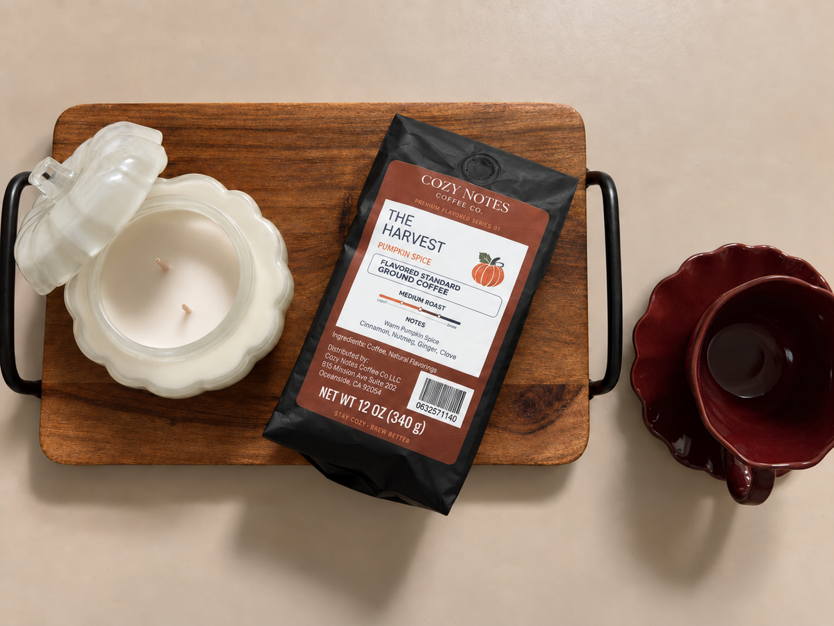 The Harvest pumpkin-spice coffee bag on a wooden kitchen tray beside a pumpkin candle and burgundy cup.