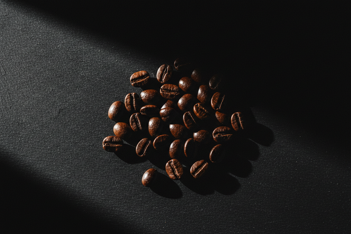 Dark oily roasted coffee beans on matte black slate with dramatic raking light — Cozy Notes Bold & Dark Roasts