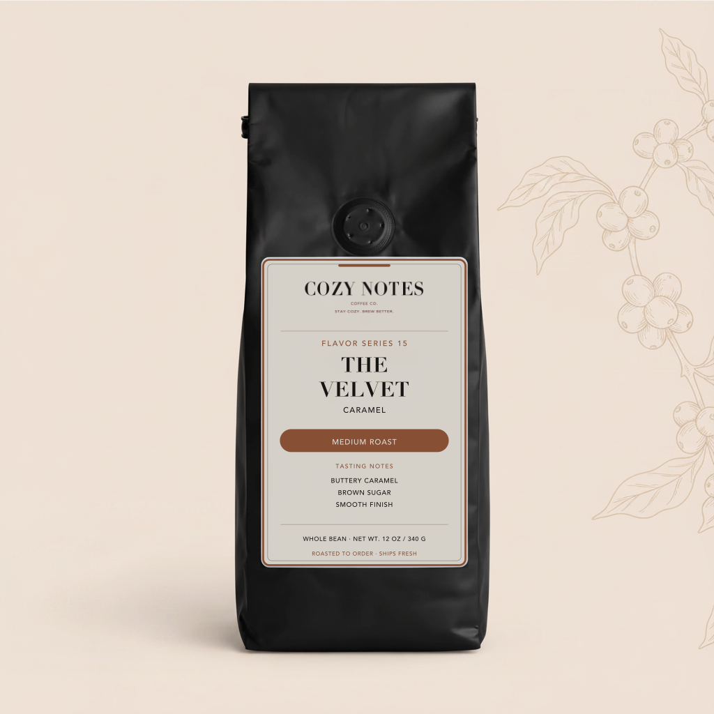 A black coffee bag from Cozy Notes, specifically 'The Velvet Caramel' medium roast, set against a warm beige background with a subtle coffee bean branch illustration on the right.