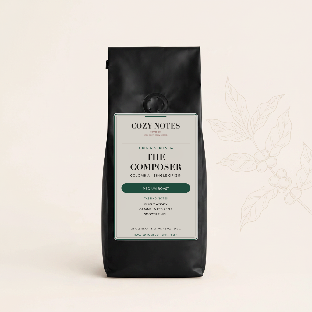 A black stand-up coffee bag labeled Cozy Notes The Composer, Colombia, Single Origin, Medium Roast, centered on a warm off-white background with a faint botanical line drawing to the right.