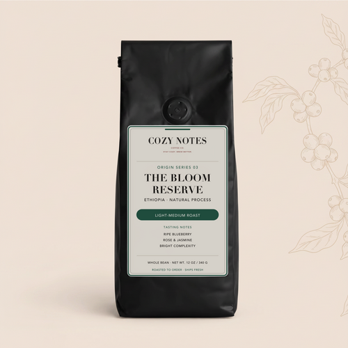 A black coffee bag from Cozy Notes, labeled 'The Bloom Reserve', standing upright against a light beige background with a subtle botanical line drawing on the right.