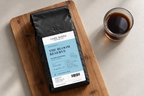 The Bloom Reserve — coffee bag with approved label beside brewed coffee.