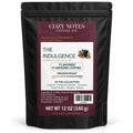 The Indulgence by Cozy Notes Coffee, six 2 oz flavored ground coffee samples in a black stand-up pouch — front product view on white