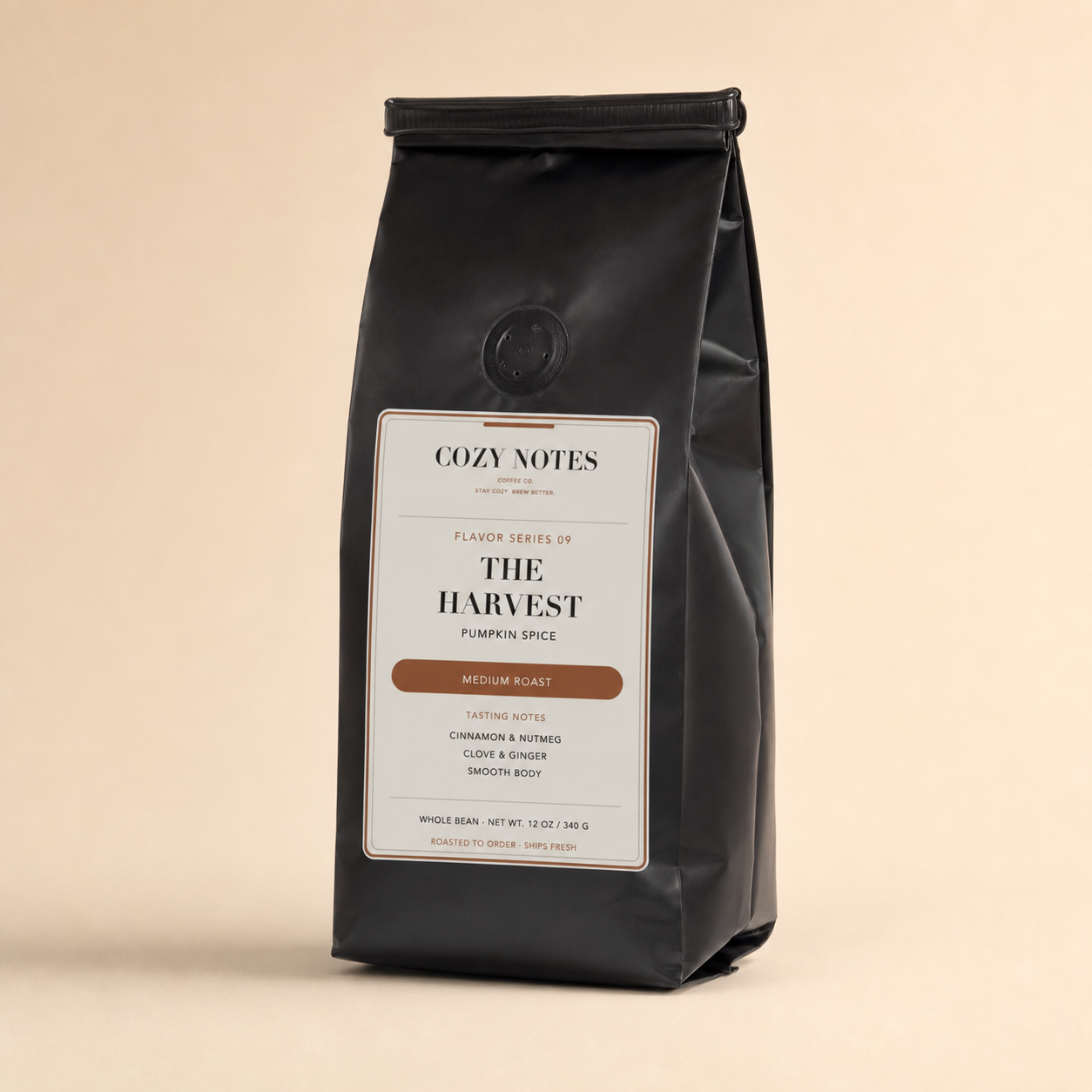 A black coffee bag with a white label reading 'Cozy Notes' and 'The Harvest Pumpkin Spice' on a warm beige background.