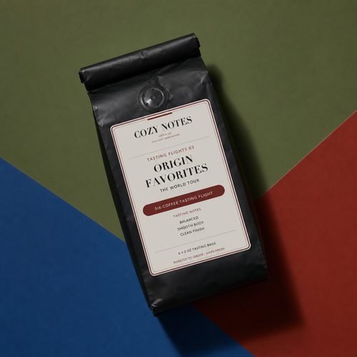 A black bag of Cozy Notes Origin Favorites coffee sits on a geometric, color-blocked background split diagonally between olive green, blue, and red.