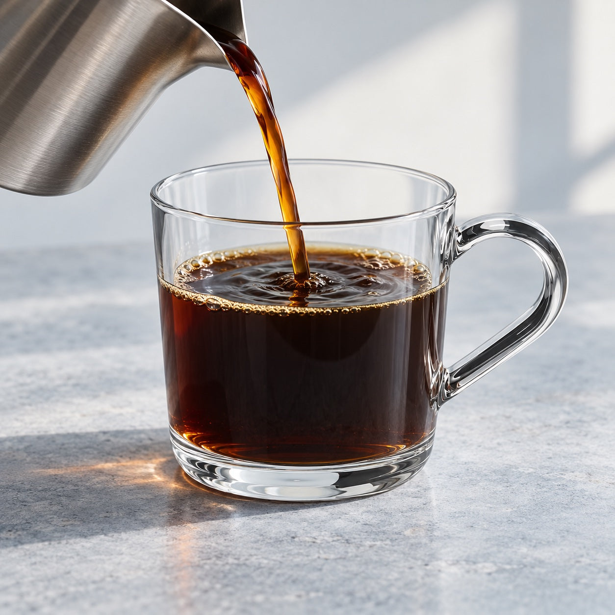 Freshly brewed coffee poured into a clear glass mug.